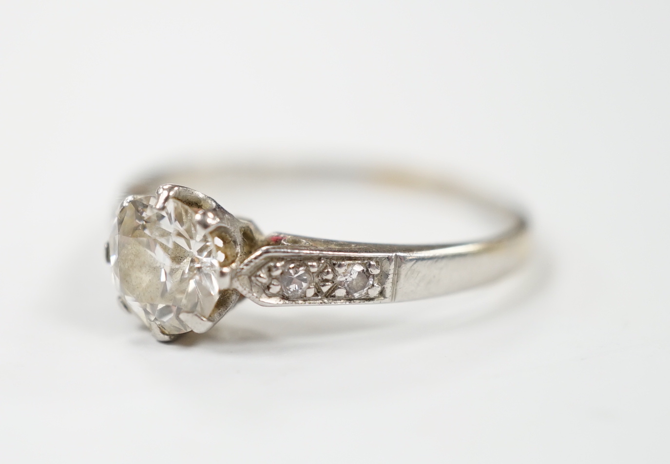 A white metal (stamped plat) and single stone diamond ring with diamond set shoulders, size M/N, gross weight 2.6 grams.